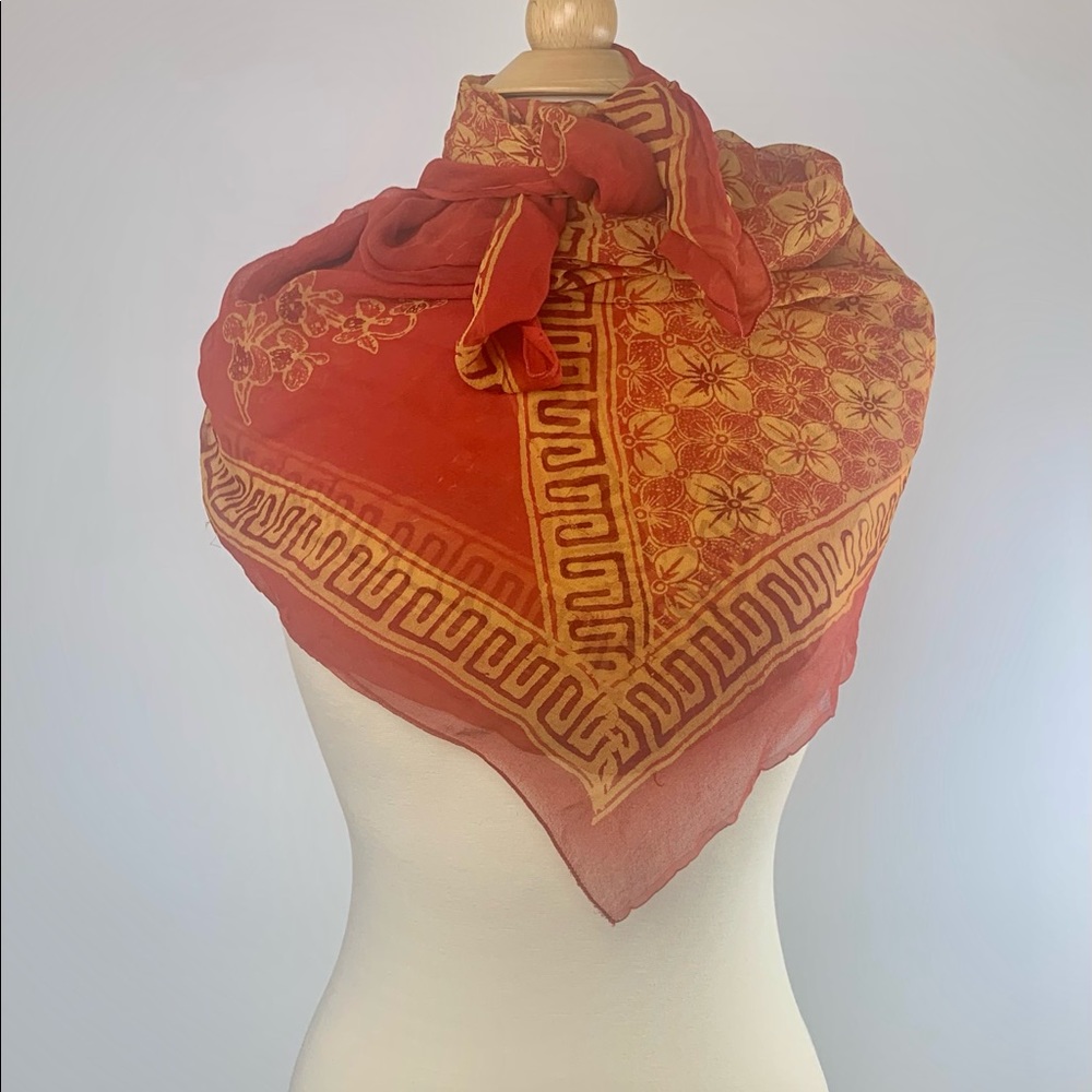 Silk crepe scarf of vibrant orange and golds in a bias floral pattern.